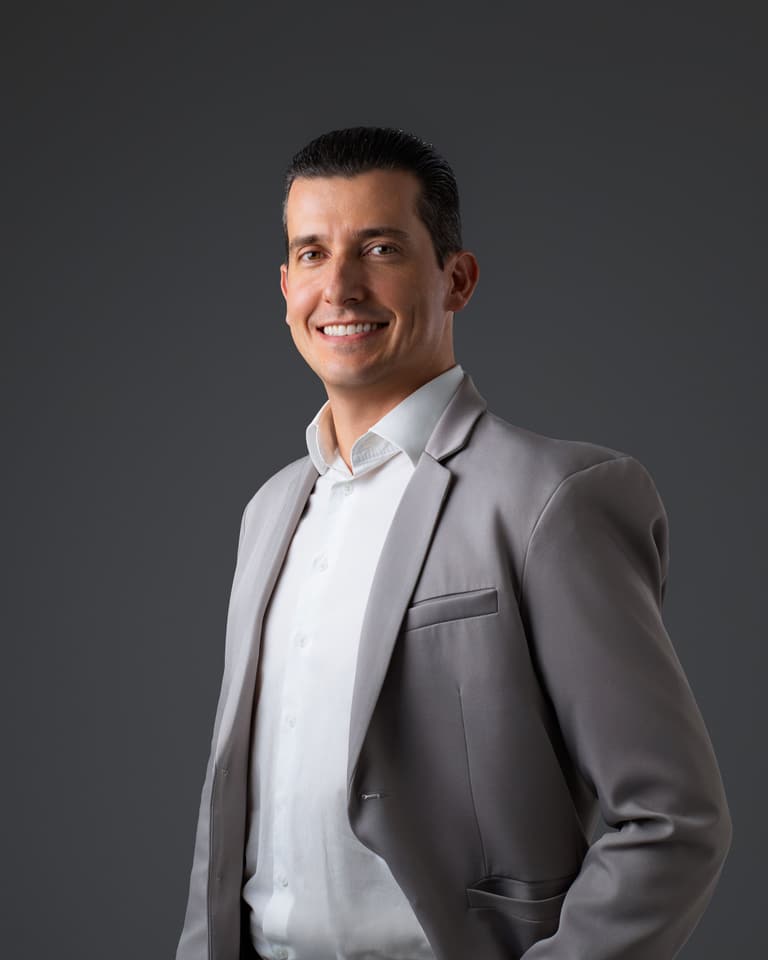 Felipe Flesch de terno cinza, em pé, sorrindo