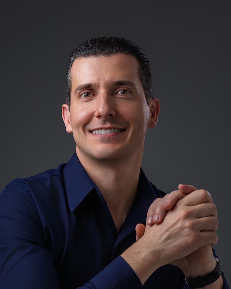 Felipe Flesch de camisa marinho, mãos entrelaçadas, sorrindo
